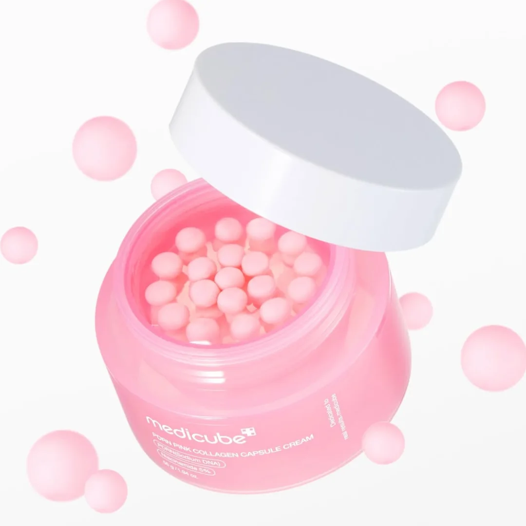 Open pink jar of Medicube PDRN Pink Collagen Capsule Cream with pink capsules floating around it against a white background.