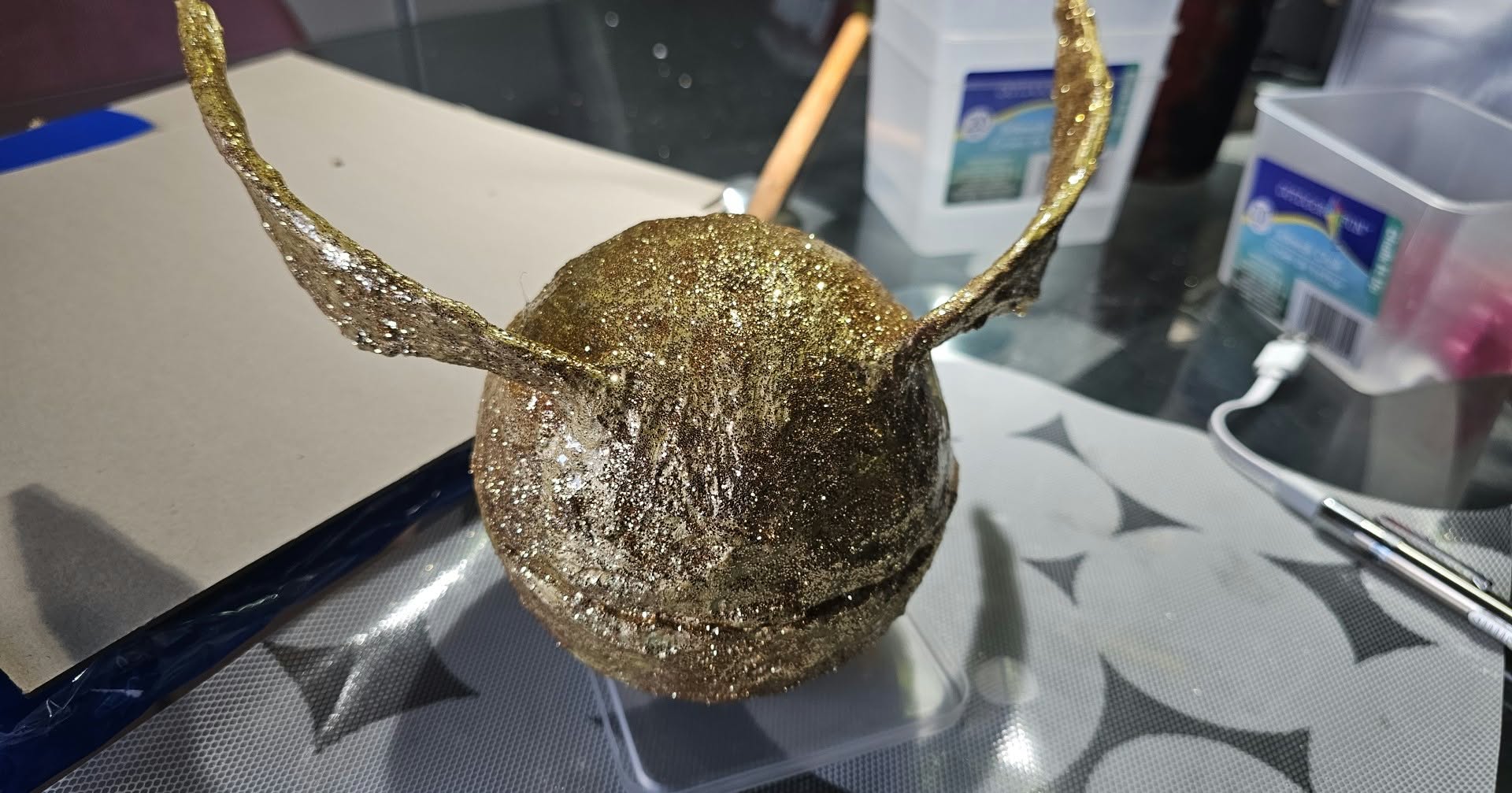 Tonima's finished Golden Snitch Timbits Holder covered in textured gold paint and glitter.