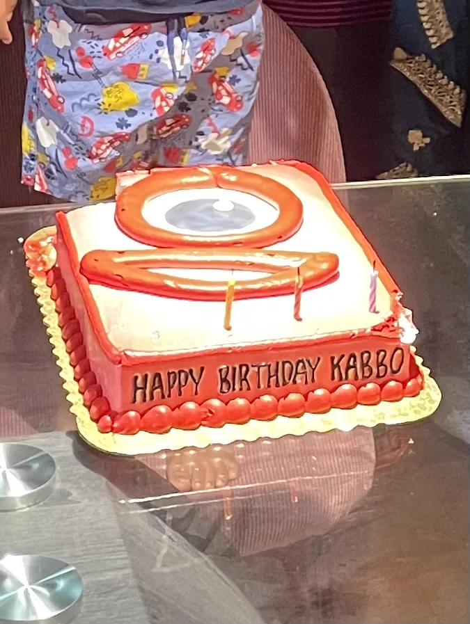 Red and white Numberblock One birthday cake on a glass table with Happy Birthday Kabbo written along the side.
